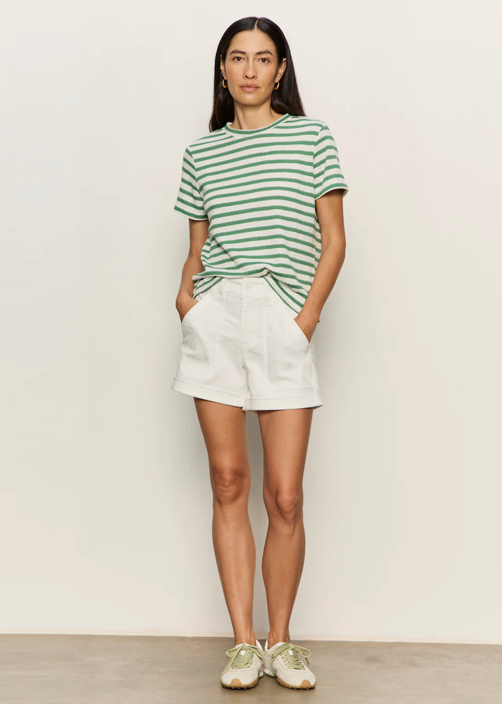 Woman wearing a green and white striped t-shirt with white shorts