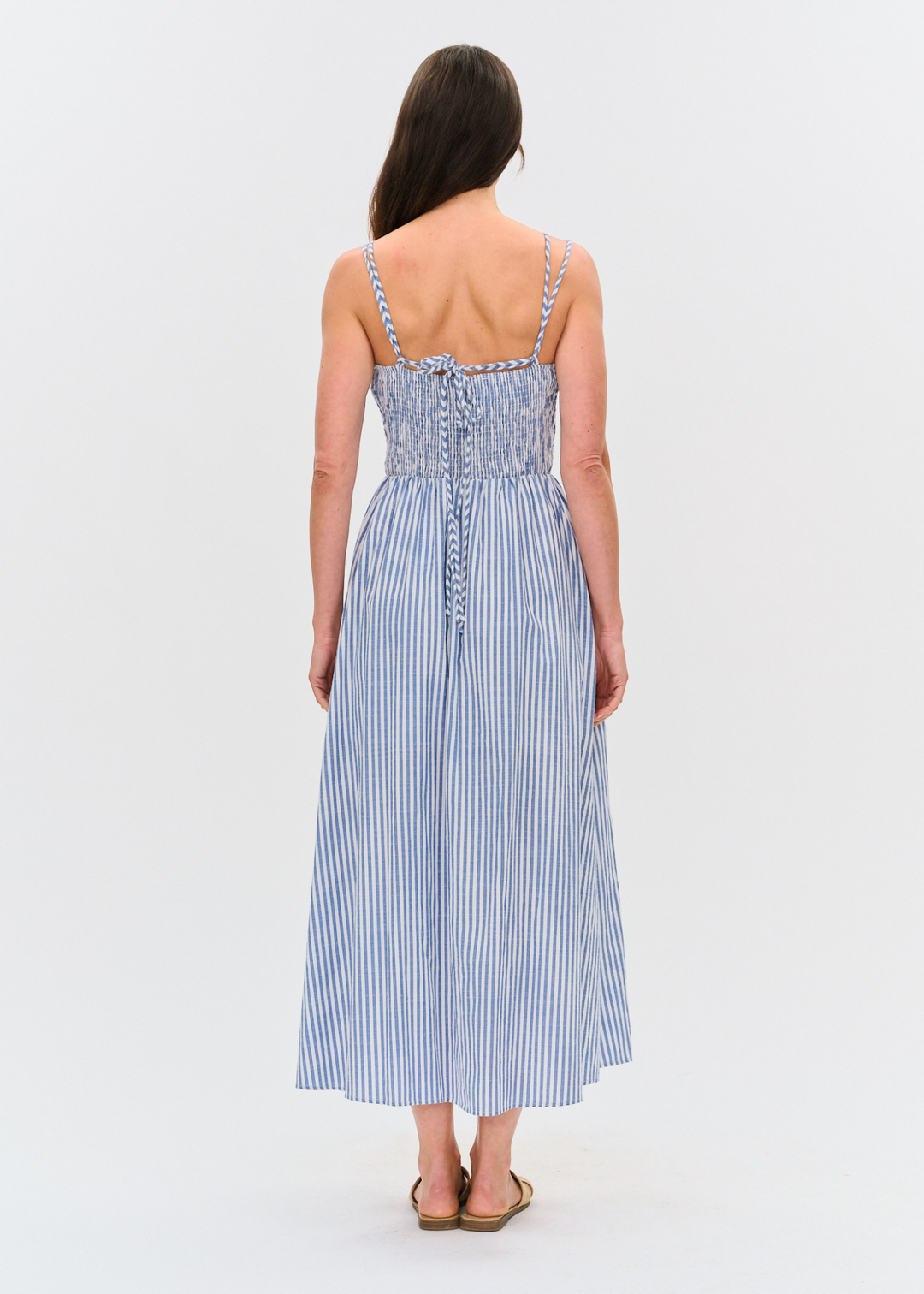 Woman turned around wearing a blue and white striped maxi dress with sandals
