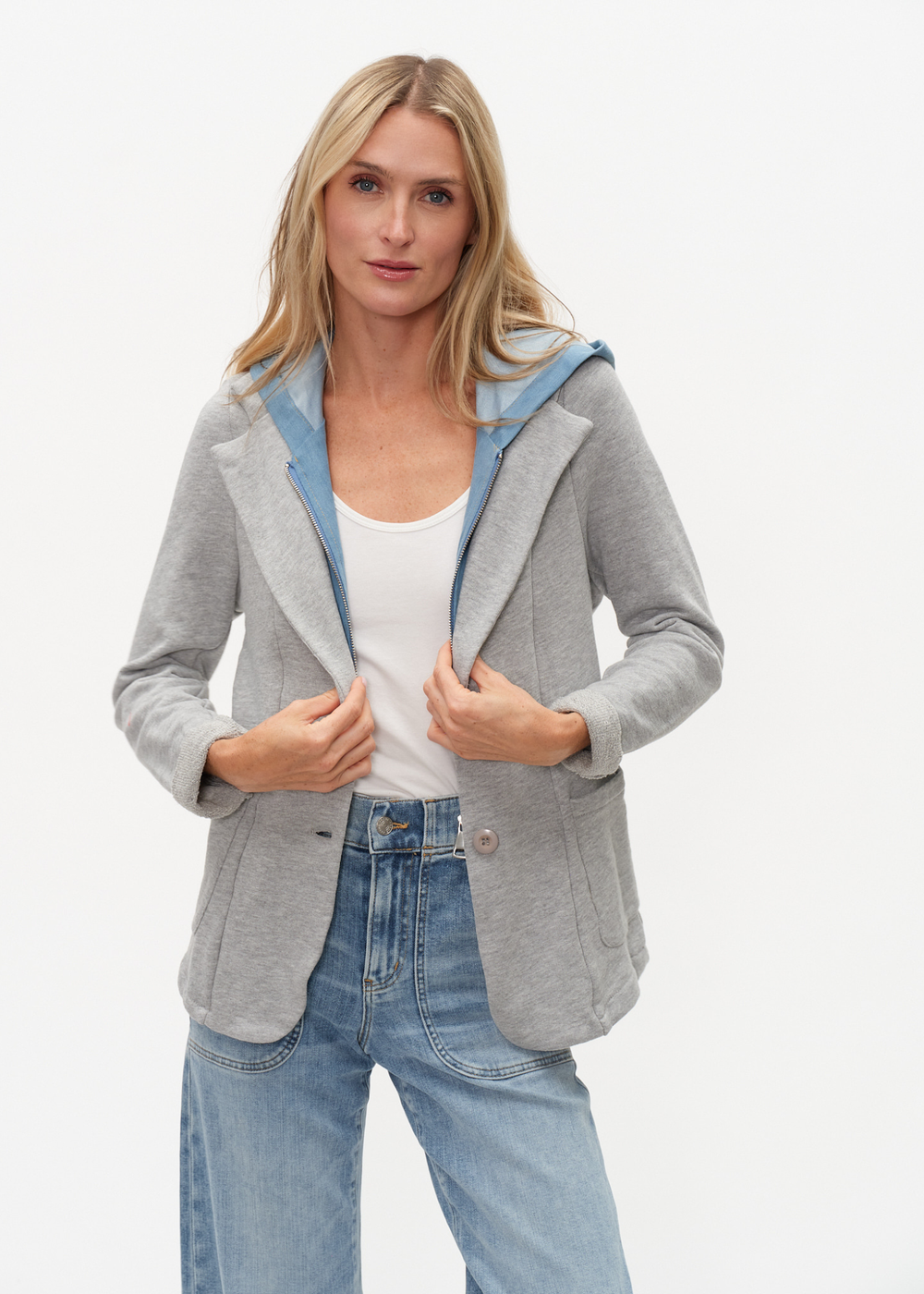 Woman wearing a denim and grey knit hooded blazer with jeans