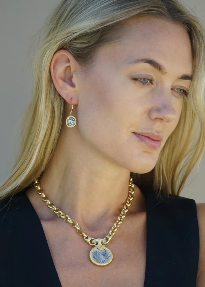 Woman wearing a gold chain necklace with a silver coin pendant