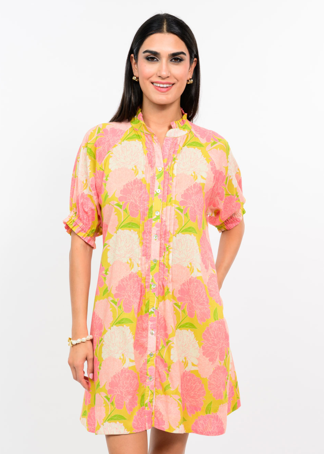 Woman wearing a pink and coral floral dress against a white background
