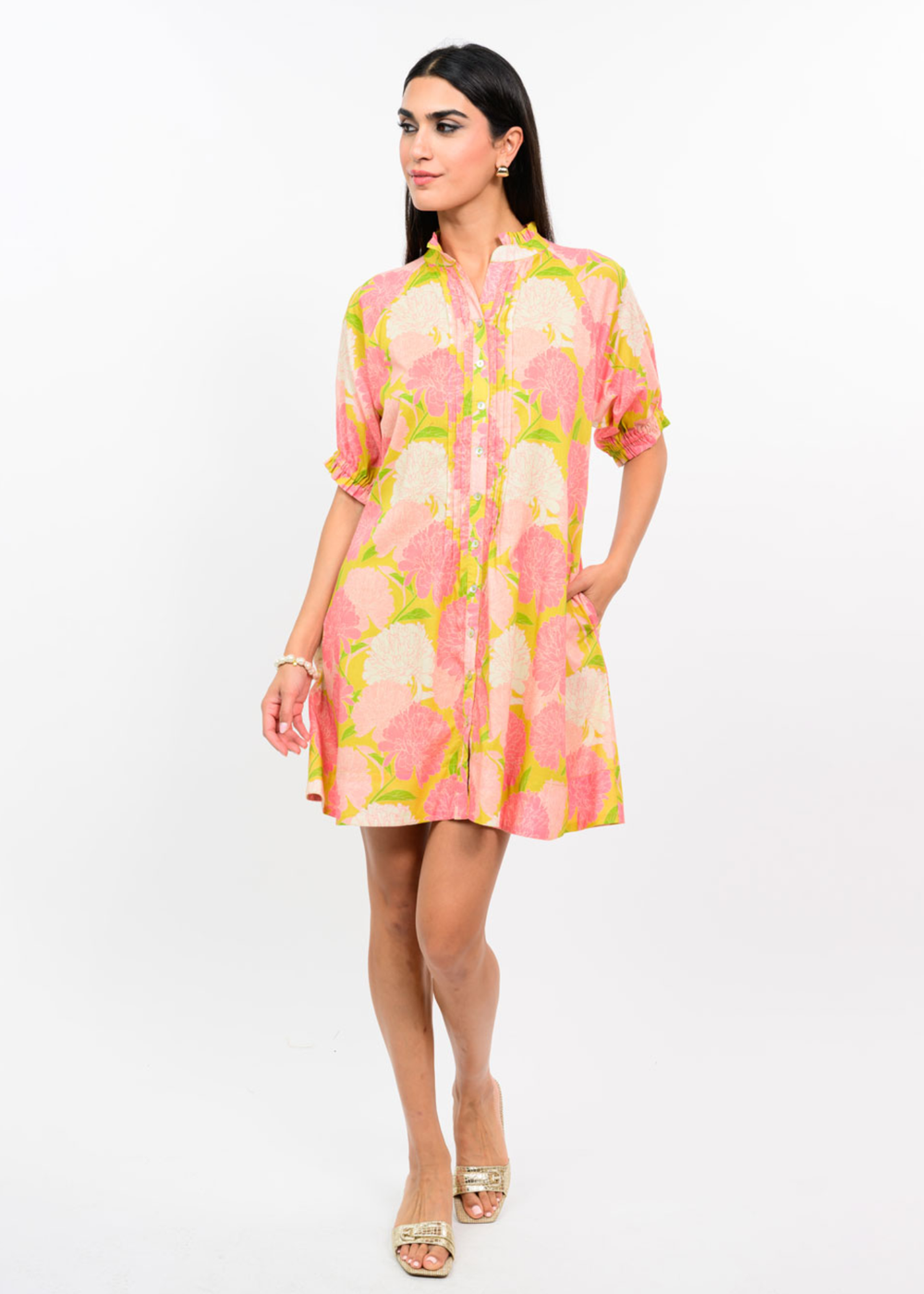 Woman wearing a pink and coral floral dress against a white background