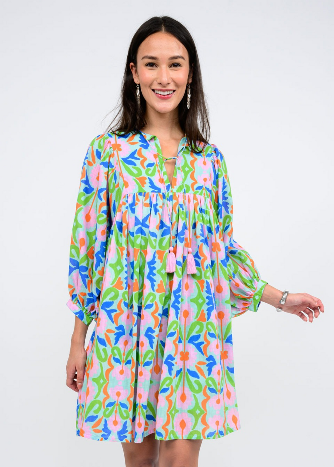 Uncle Frank green, blue, orange, and pink abstract floral print mini dress with long sleeves, split neckline, neck ties, and pleated skirt