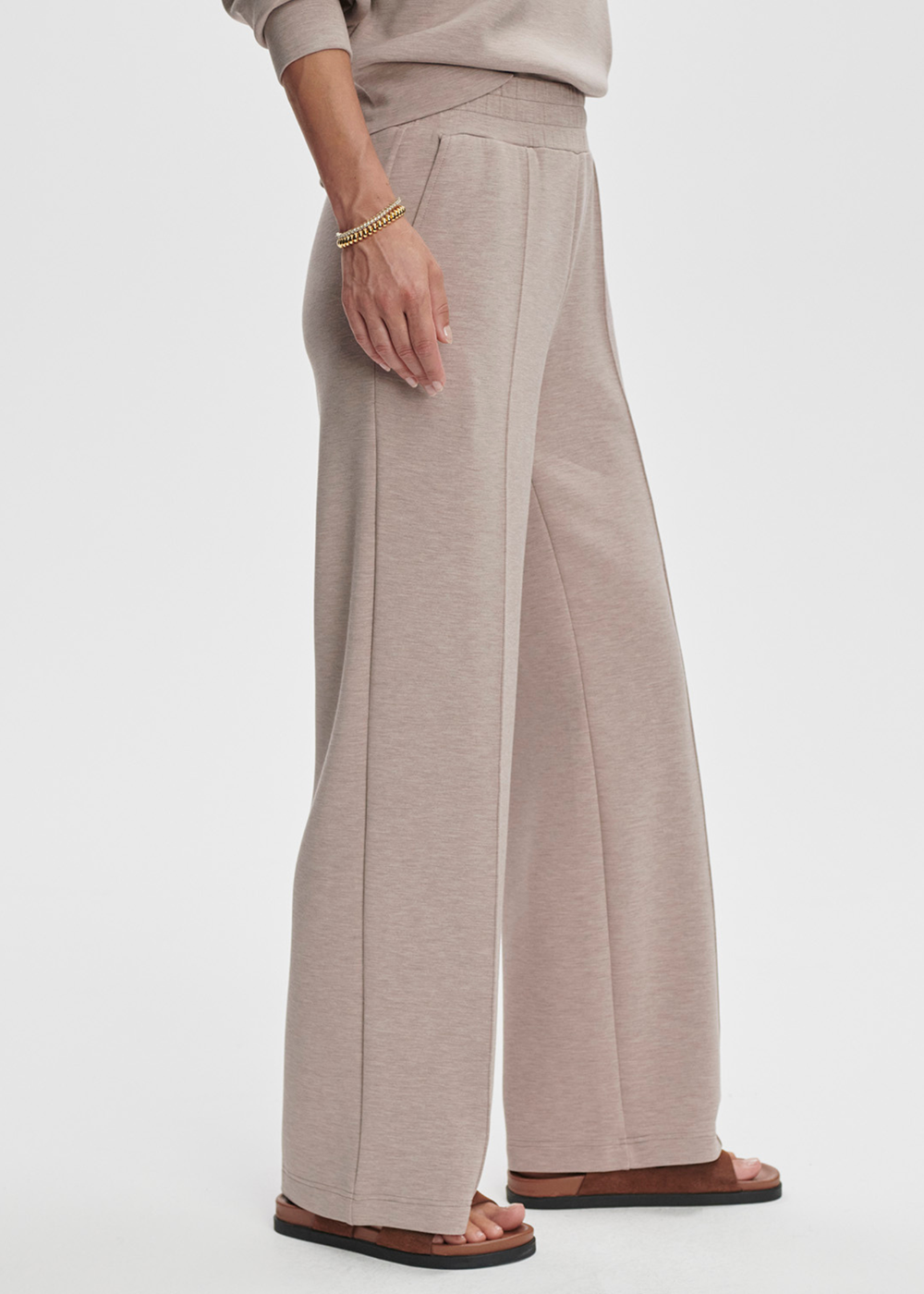 Woman wearing taupe wide leg pants against a white background