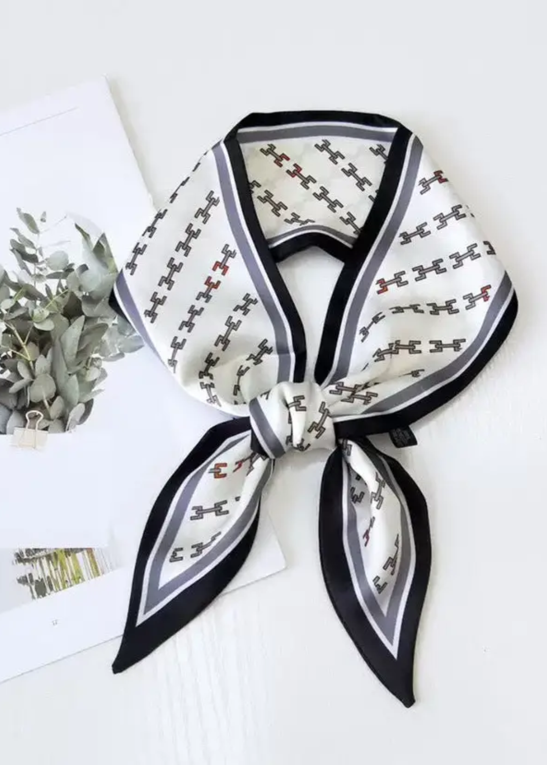 White scarf with black trim and a link pattern