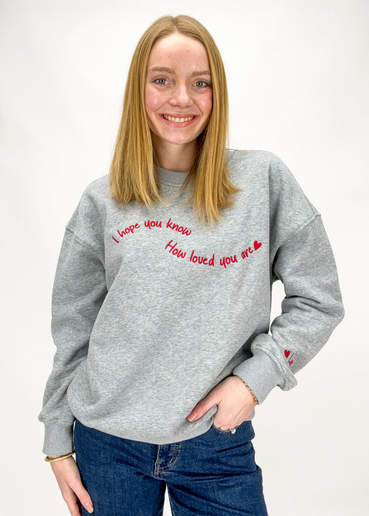 Person wearing a gray sweatshirt with red text on a white background