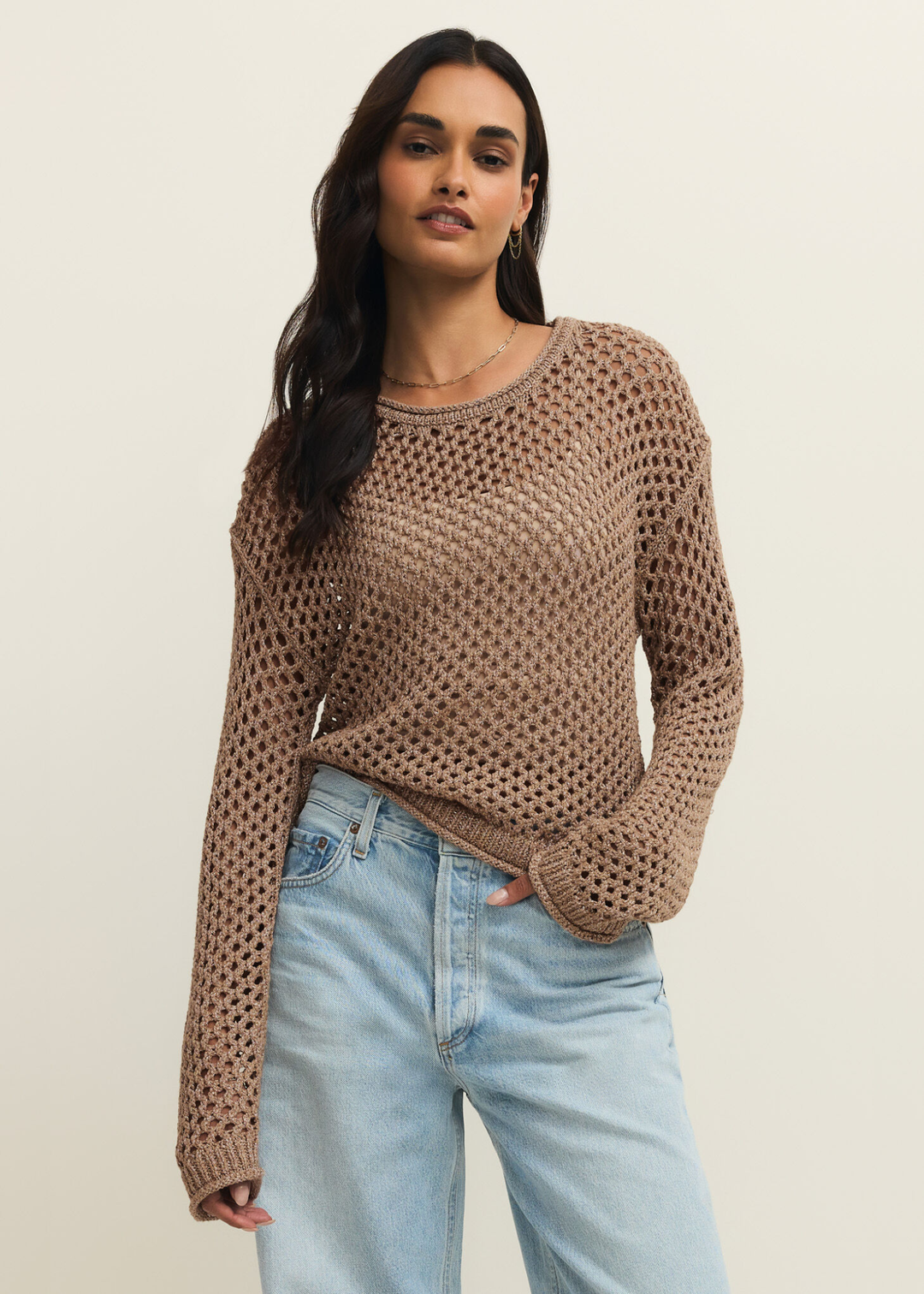 Woman wearing a brown shimmer sweater with jeans and hand in pocket