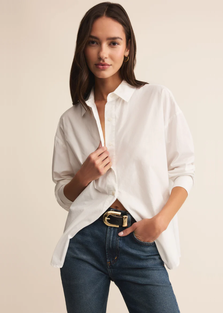 Woman wearing a white button down shirt with jeans and holding collar