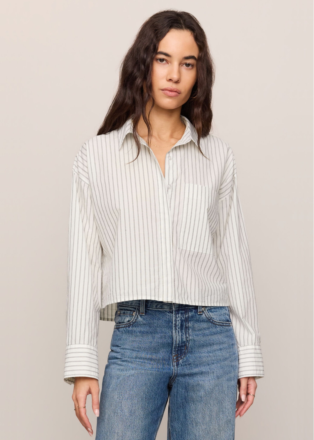 Woman wearing a white striped button down top with jeans