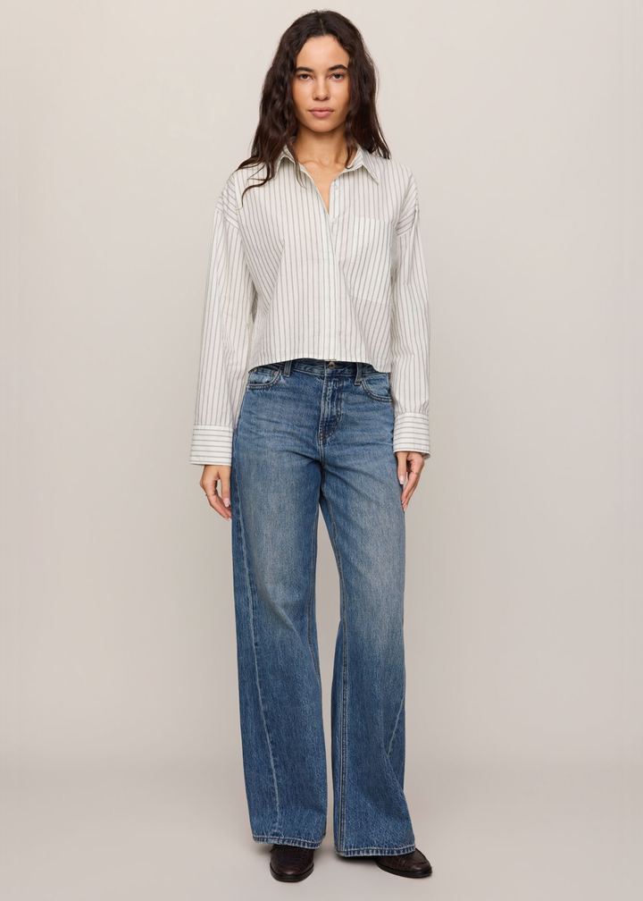 Woman wearing a white striped button down top with jeans