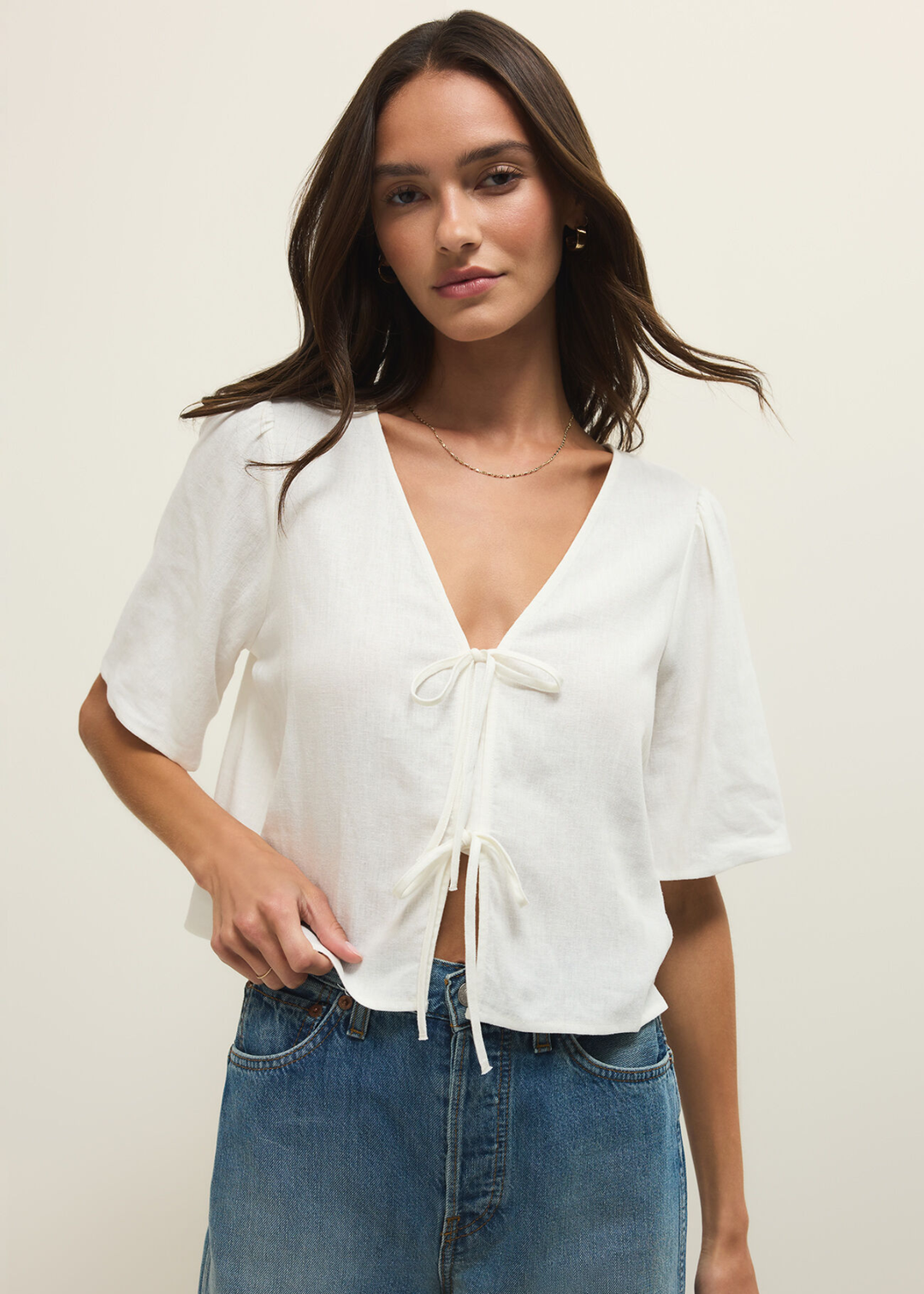 Woman wearing a short sleeve white linen tie front top with jeans