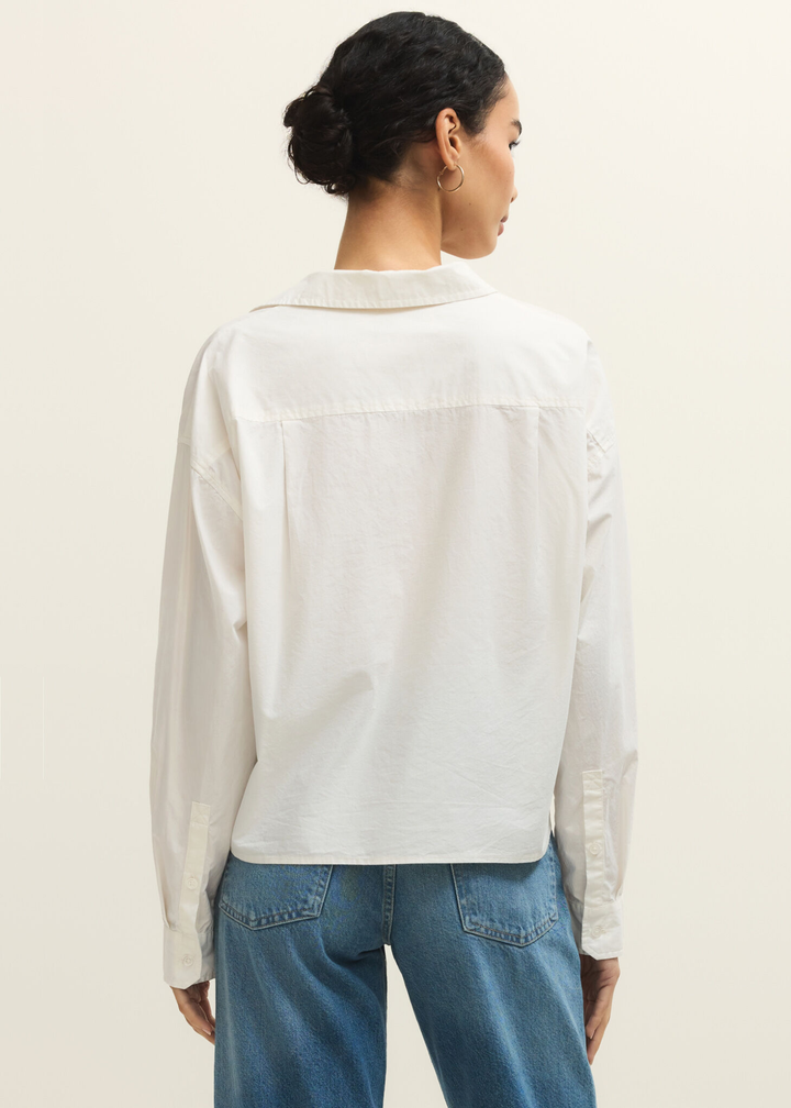 Woman turned around wearing a white button down top with jeans