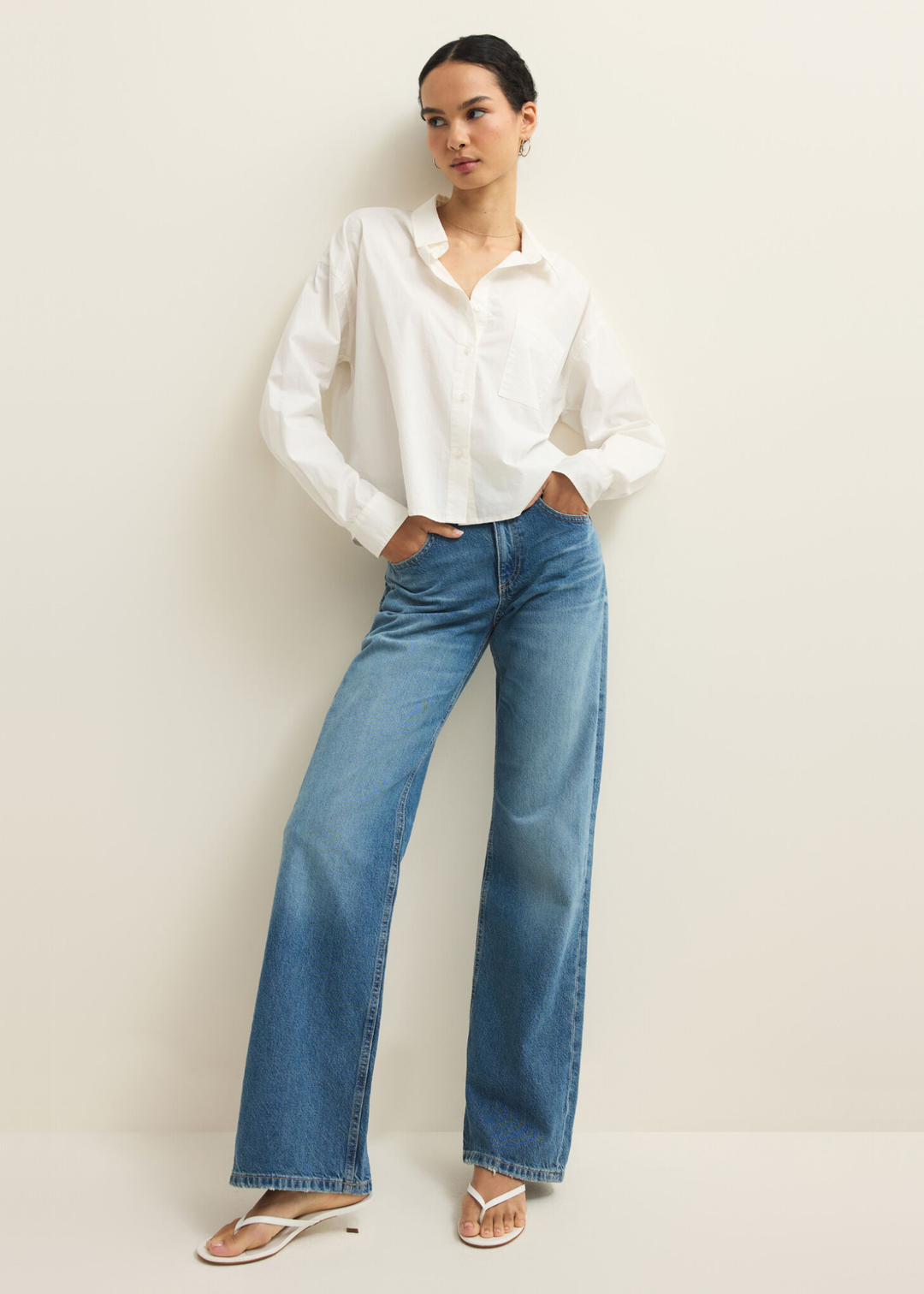 Woman wearing a white button down top with jeans