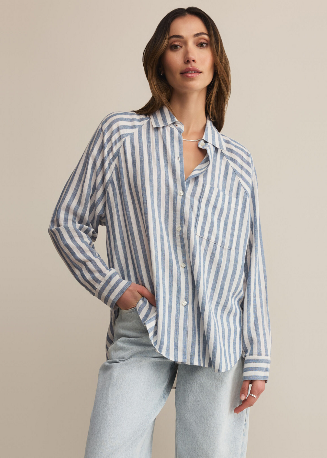 Woman wearing a long sleeve button down with white and blue vertical stripes