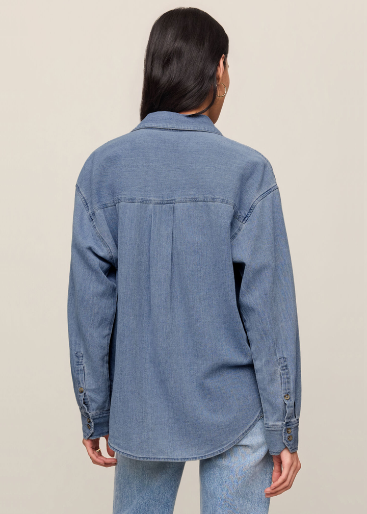 Woman turned around wearing a denim button down top and jeans