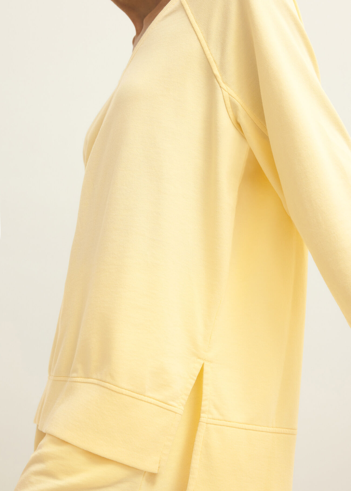 Close up of a woman wearing a yellow v-neck sweatshirt with yellow shorts