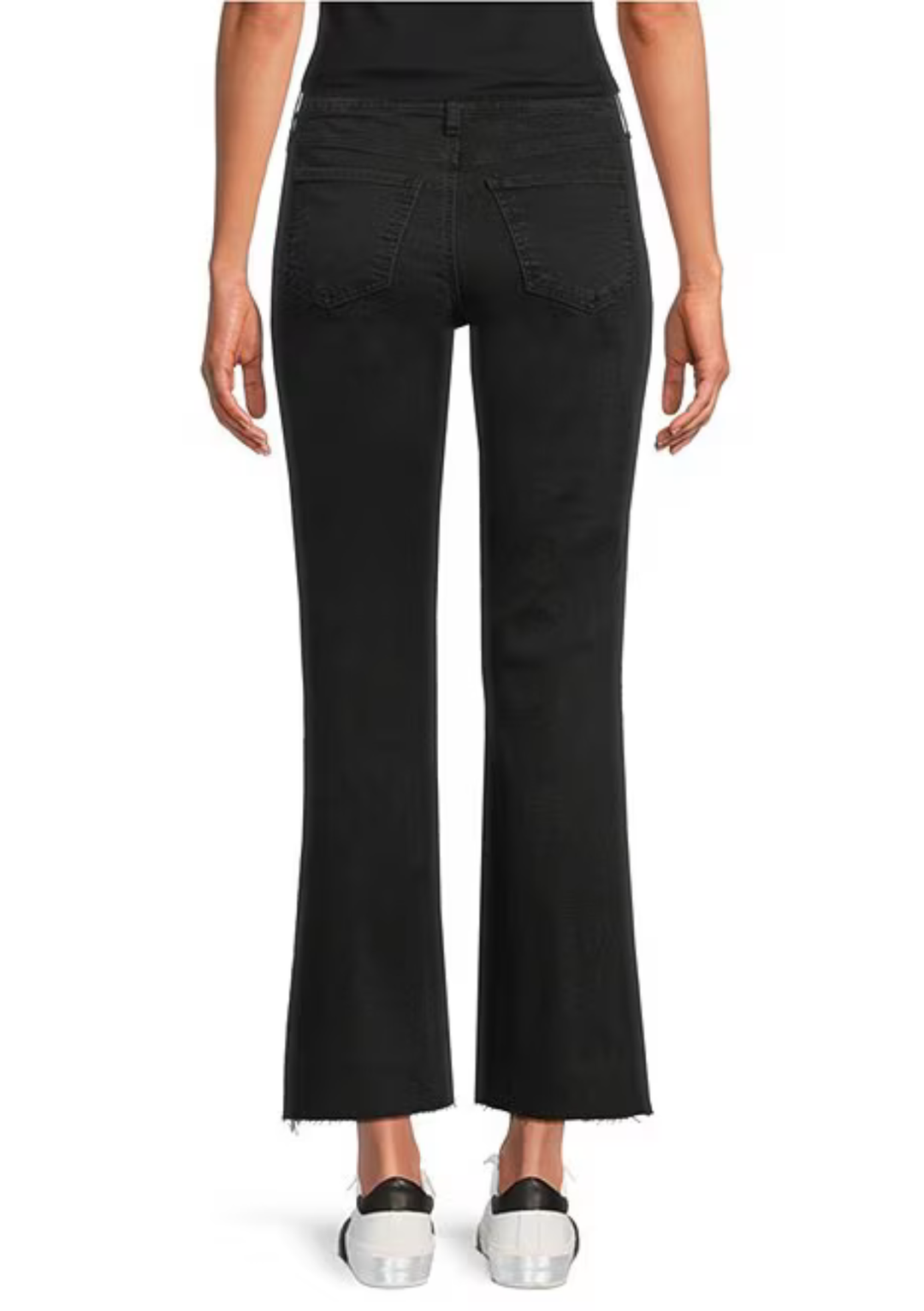 Rear view of a model wearing black flared jeans with a cropped hem and frayed edges, paired with white sneakers, on a white background.