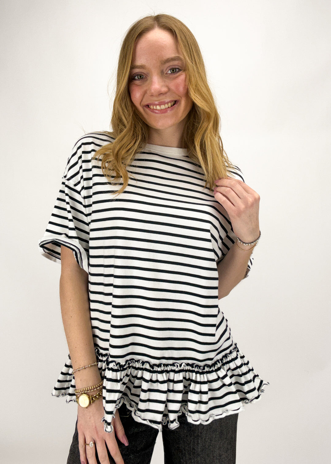 Woman wearing a black and white striped shirt with ruffled bottom on a white background