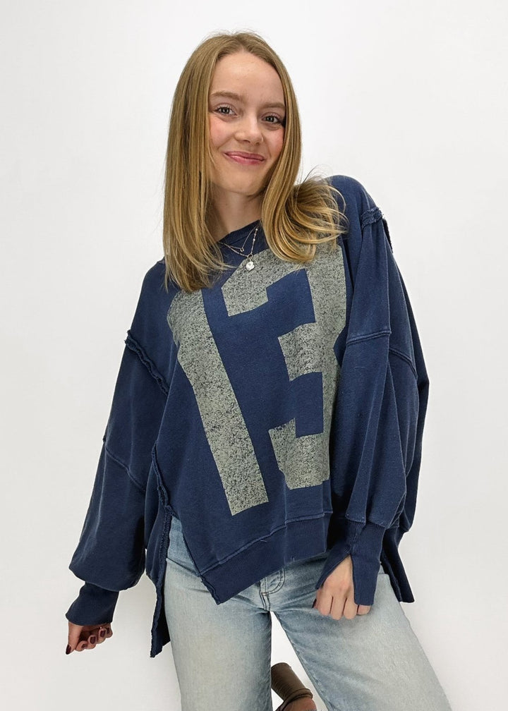 woman wearing navy blue oversized "13" graphic crew neck sweatshirt with exposed seam details