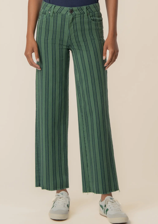 A person wearing green wide-leg cropped pants with thin dark vertical stripes, paired with white sneakers, shown from the waist down against a plain light beige studio background.