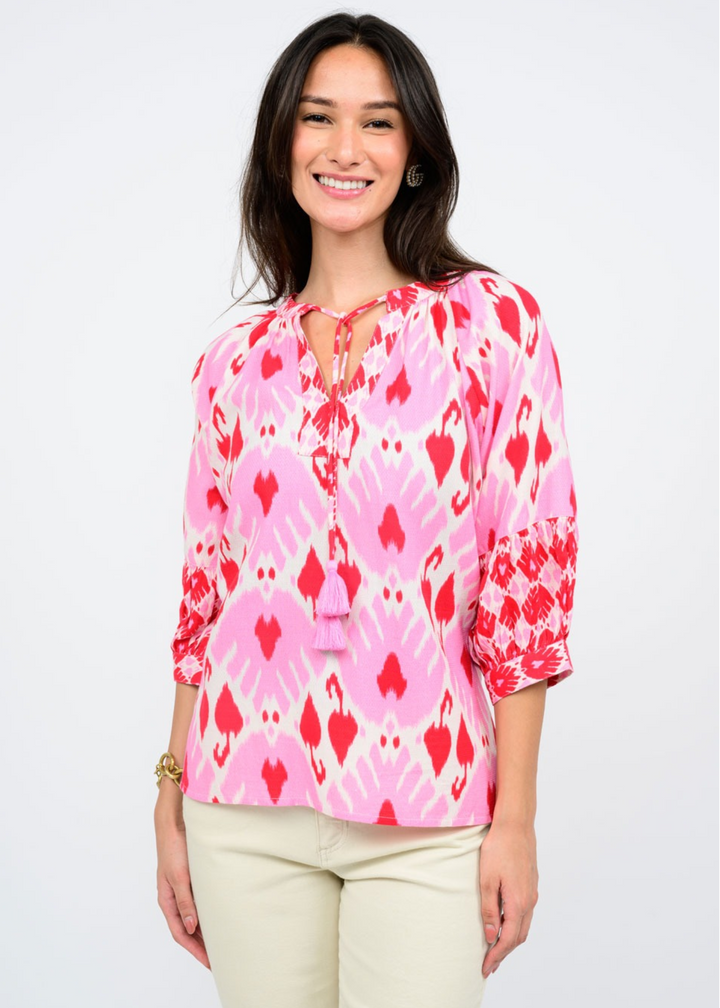 pink, red, and white abstract print top with split neckline, neck ties, and 3/4 sleeves