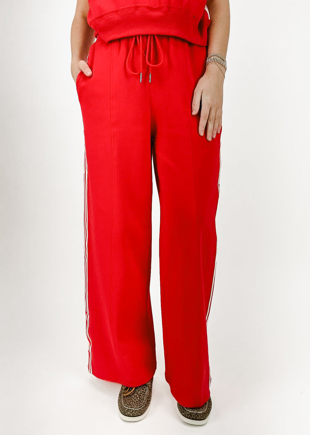 woman wearing red wide leg drawstring sweatpants with white stripes down sides