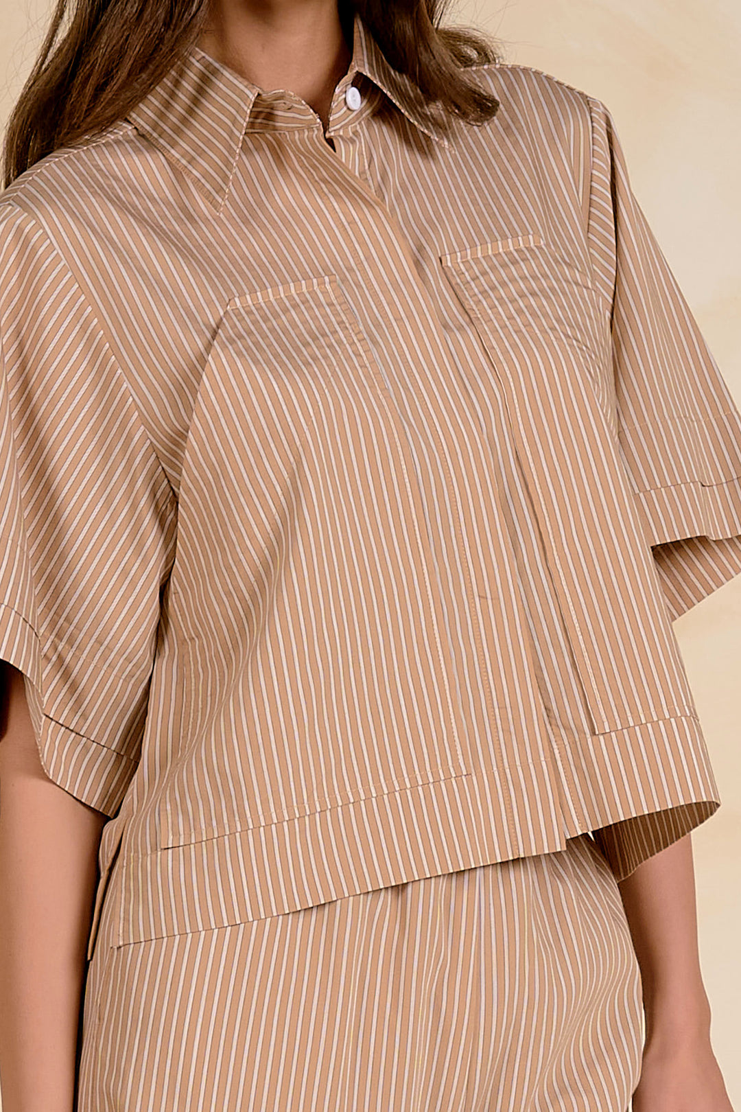 Beige striped shirt worn by a person on a beige background