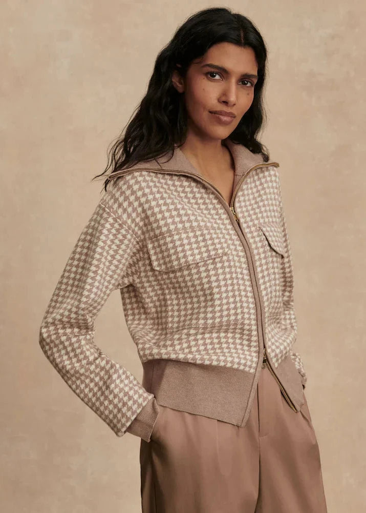 Woman wearing a houndstooth pattern jacket against a beige background