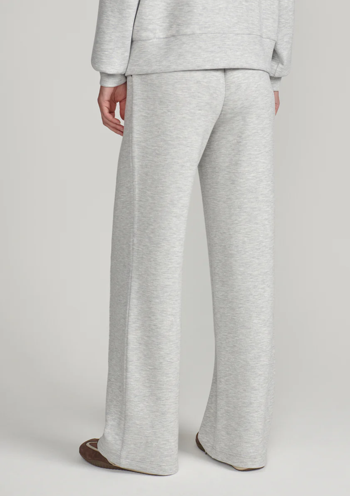 A person shown from the back wearing light heather gray wide-leg sweatpants and a matching sweatshirt against a plain light gray studio background.
