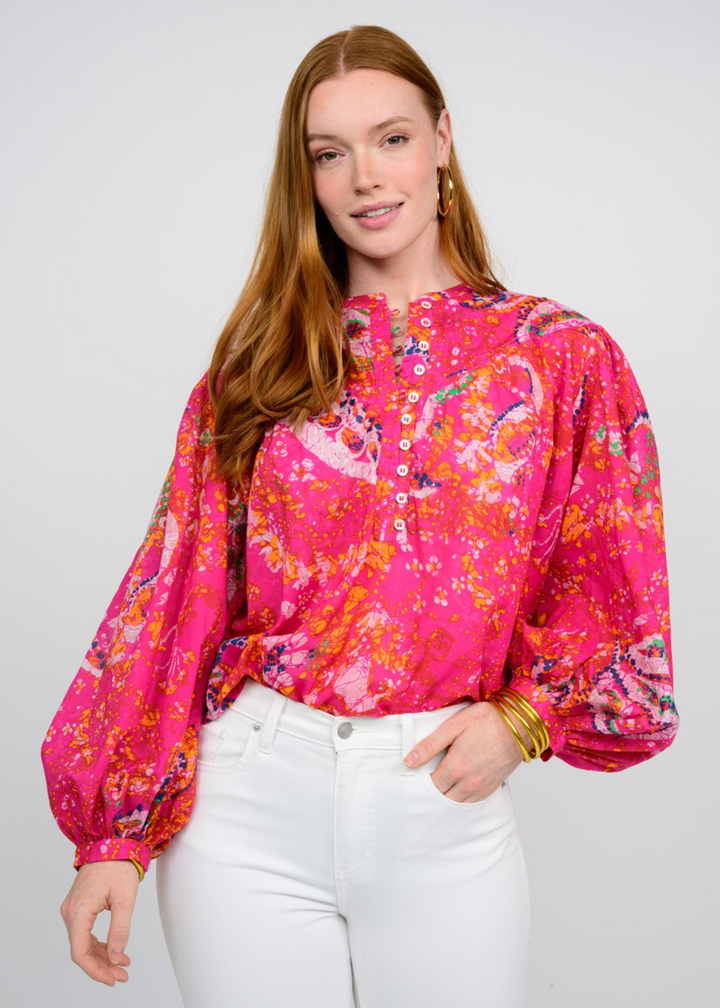 woman wearing fuchsia patterned top with 1/2 button down front and long balloon sleeves