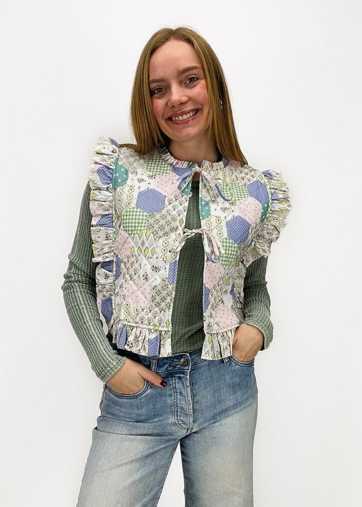 woman wearing pastel quilted tie front ruffle vest over sage thermal long sleeve tee styled with light wash Kut From the Kloth jeans