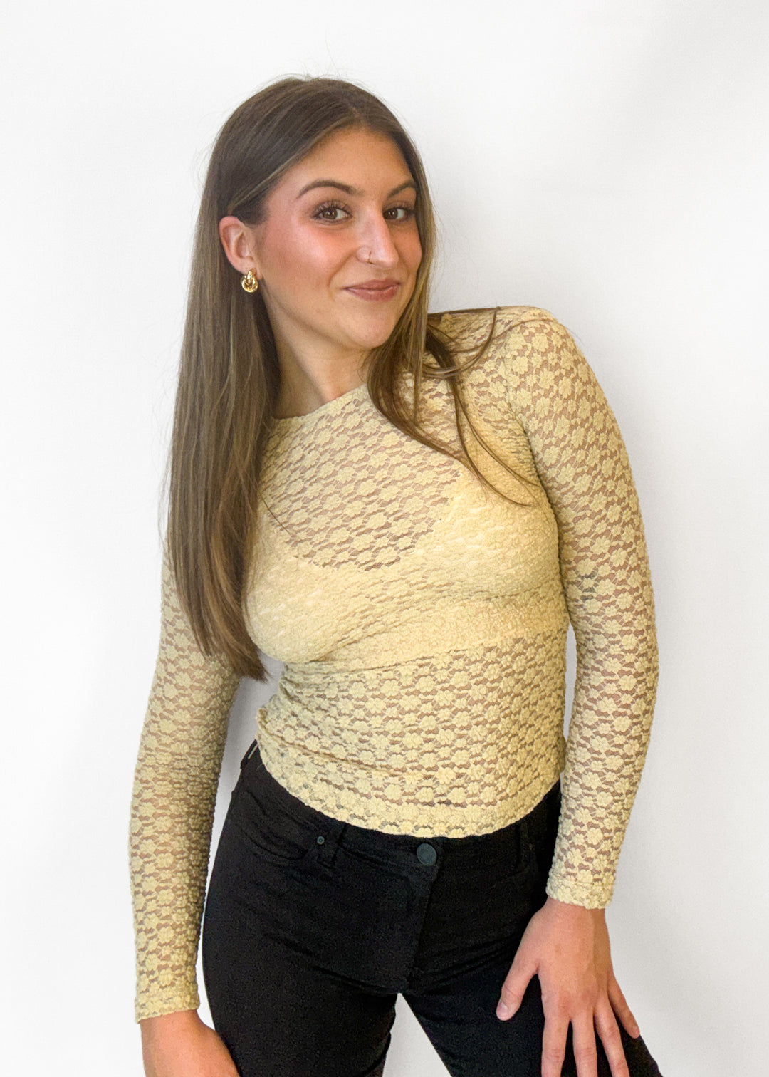 A woman modeling a beige mesh long-sleeve knit top against a plain white background.