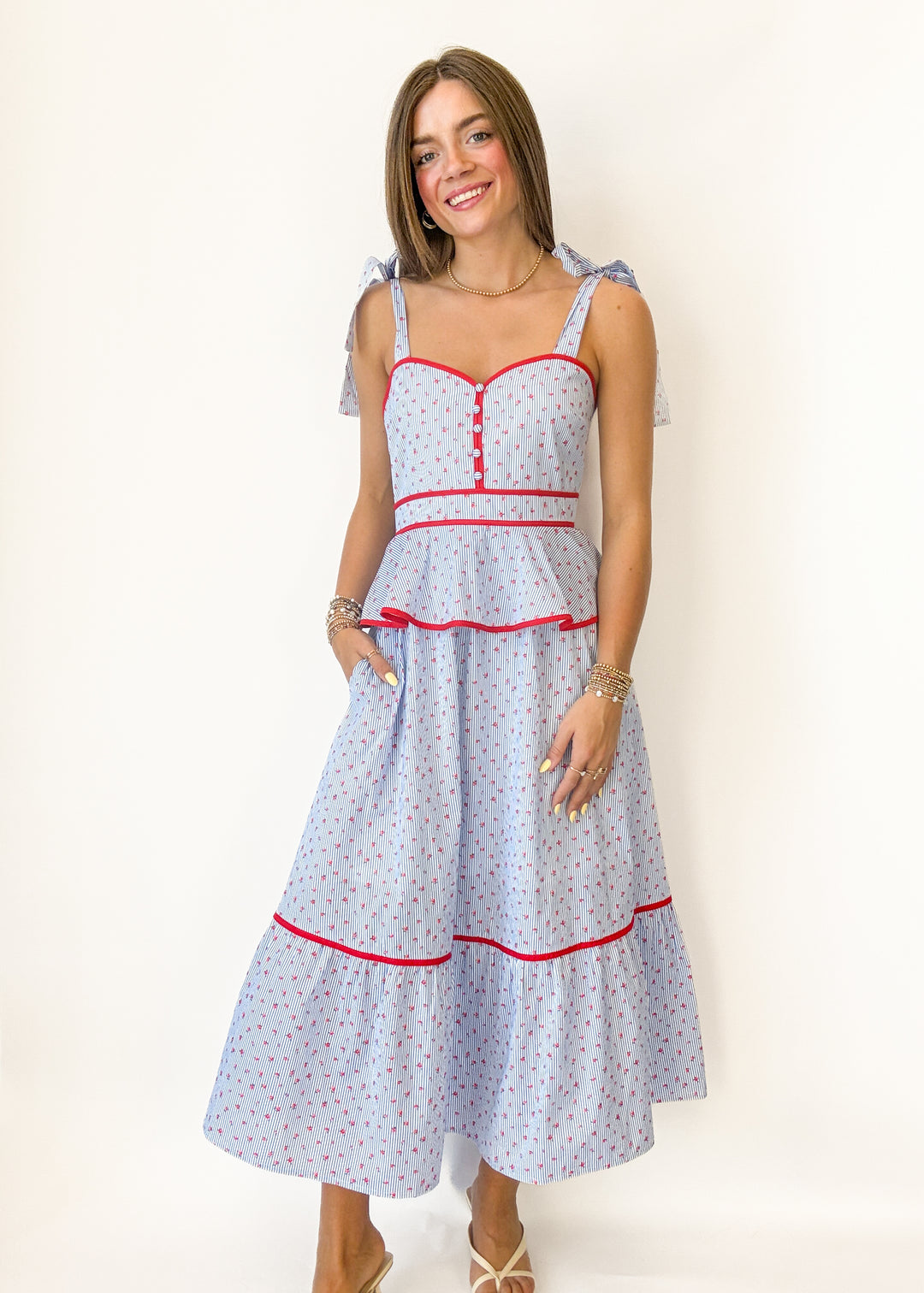 Woman wearing a light blue dress with red accents on a white background