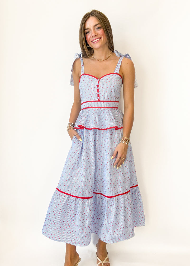 Woman wearing a light blue dress with red accents on a white background