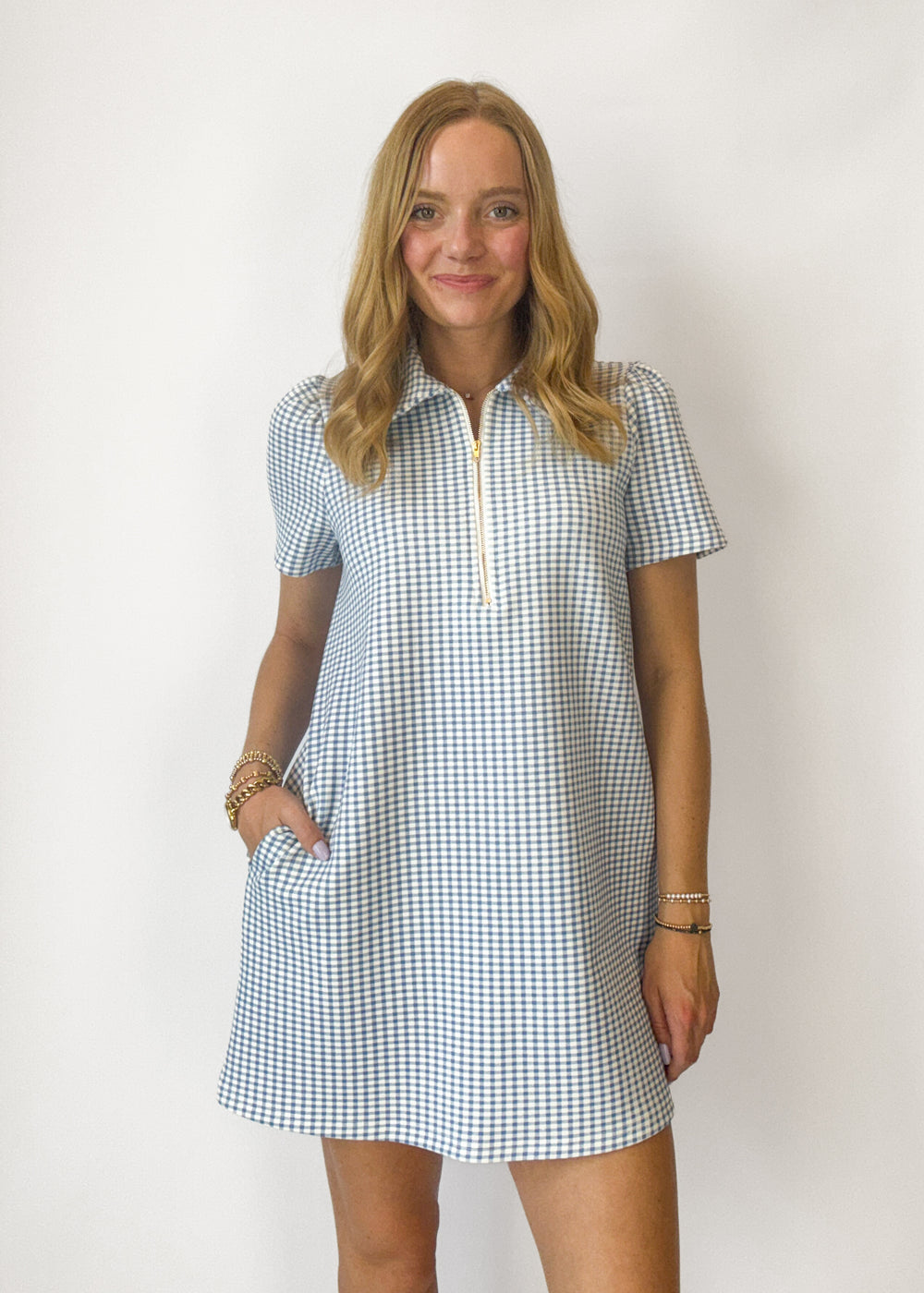 Woman wearing a blue and white checkered dress against a plain background