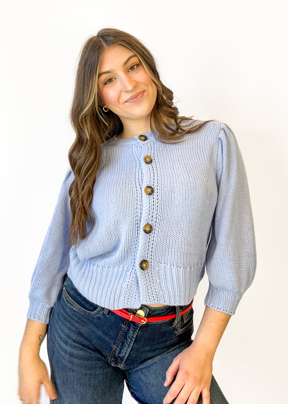 Woman wearing a light blue cardigan with buttons on a white background
