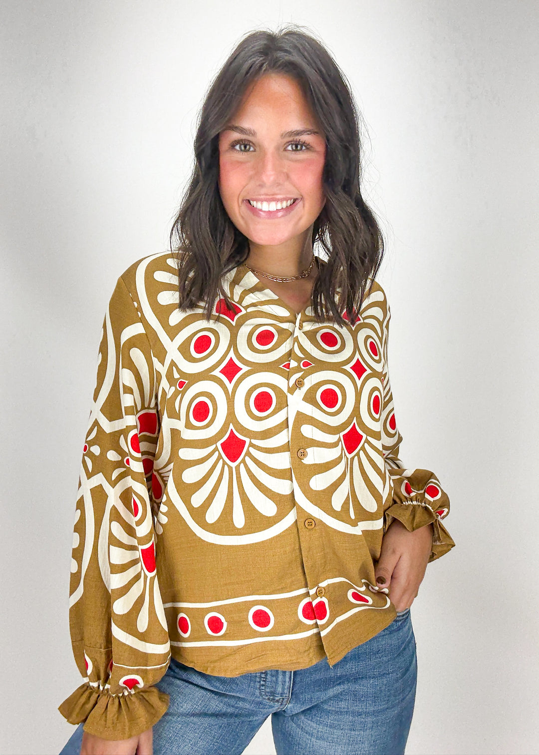 Woman wearing a patterned blouse with red and white design 