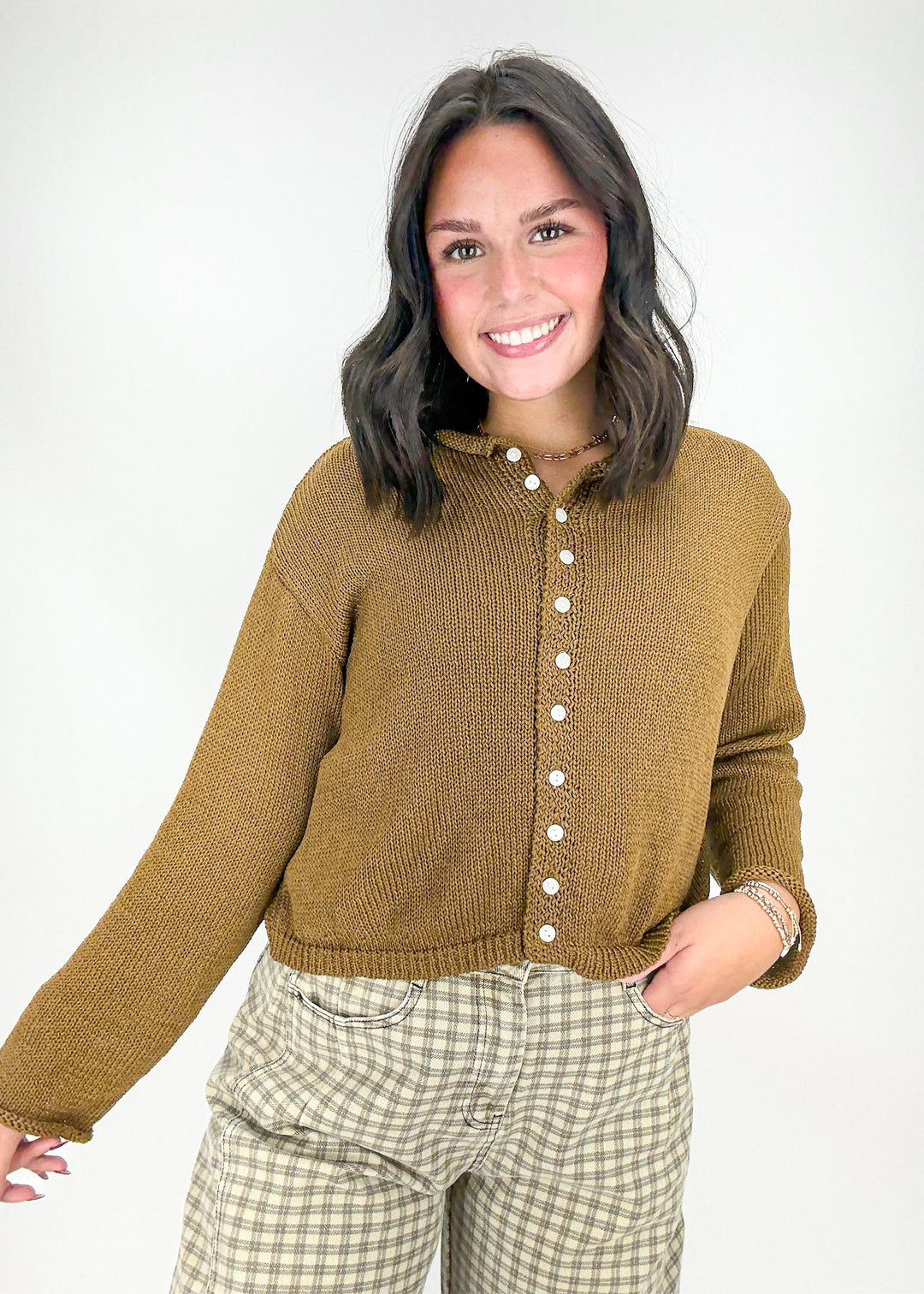 Woman wearing a mustard yellow knitted cardigan and plaid pants 