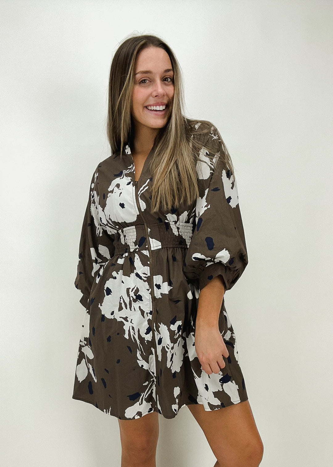 Women's brown mini dress with white and navy floral print, puff sleeves, and a smocked waist for a stylish and comfortable fit