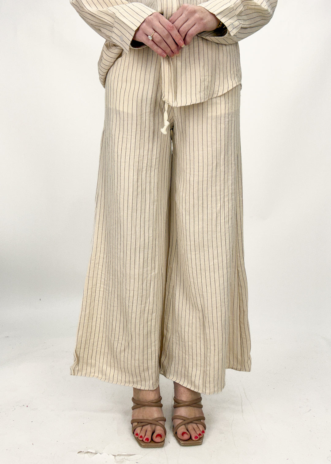 Person wearing beige ribbed pants and a matching top on a white background
