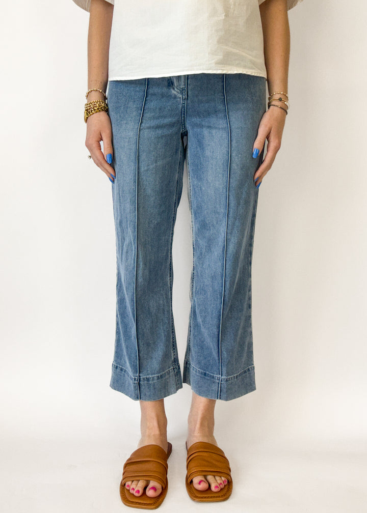 Person wearing blue jeans and brown sandals on a white background