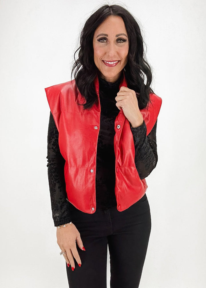 woman wearing red faux leather puffer vest over black layering top with black jeans