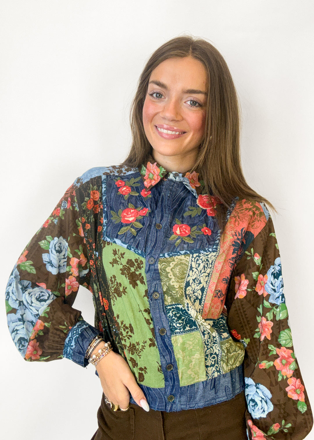 Woman wearing a blue, green, and brown floral embroidered button down