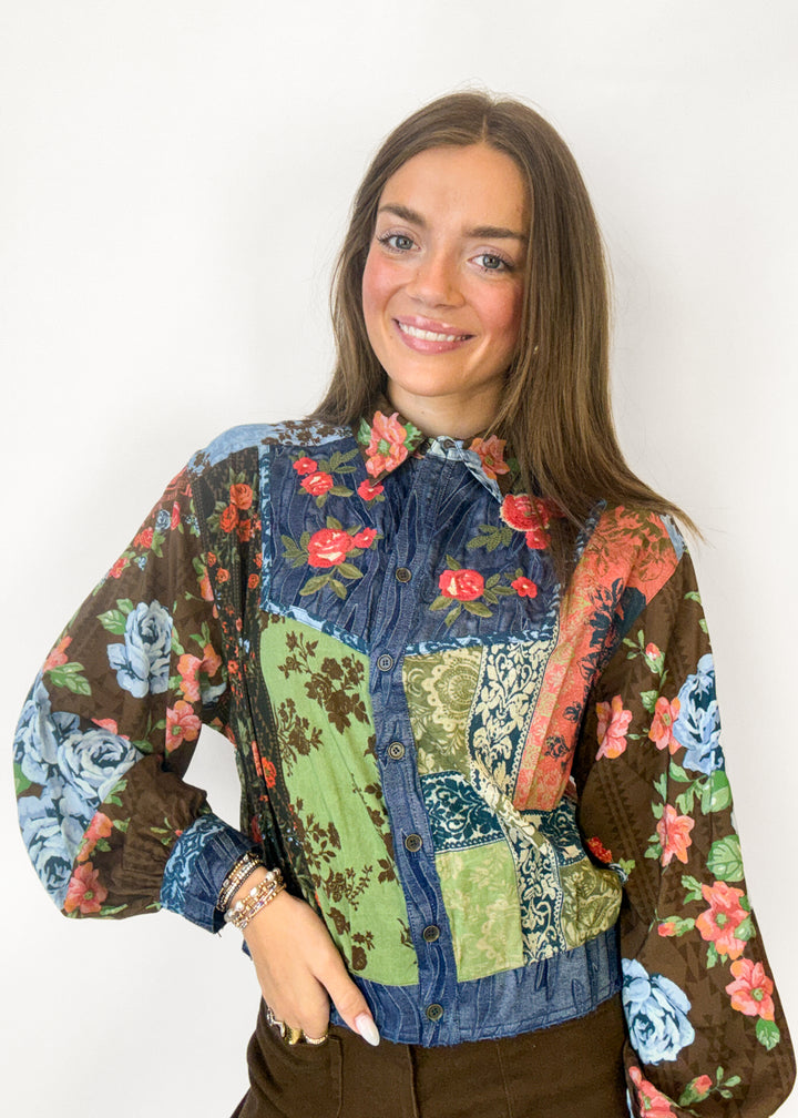 Woman wearing a blue, green, and brown floral embroidered button down
