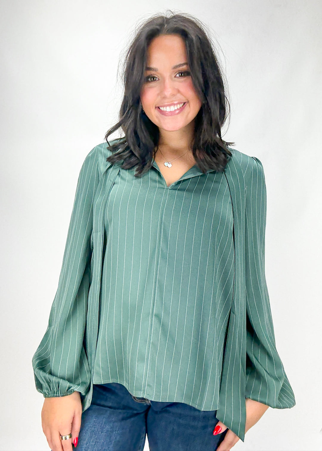 Woman wearing a green pinstripe blouse against a white background