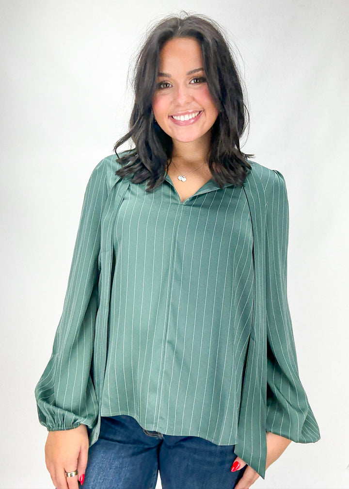 Woman wearing a green pinstripe blouse against a white background