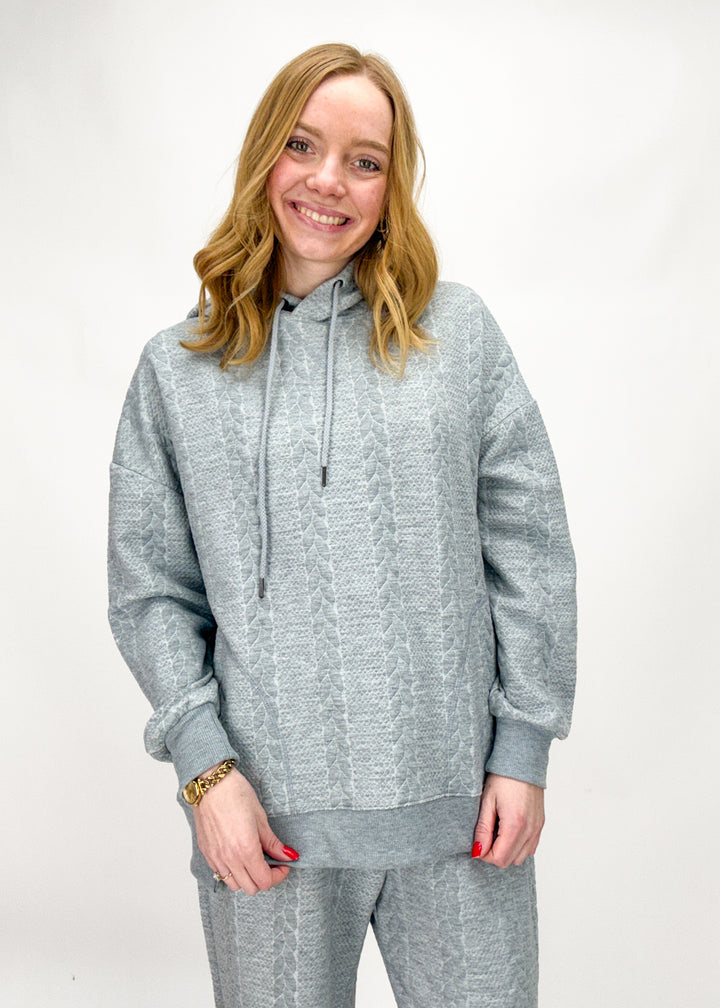 Person wearing a gray tracksuit on a white background