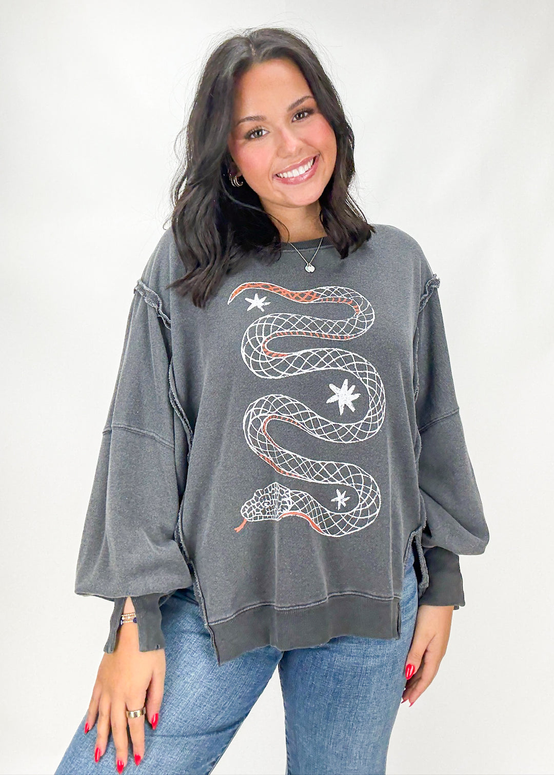 Woman wearing a gray sweatshirt with a snake design on a white background