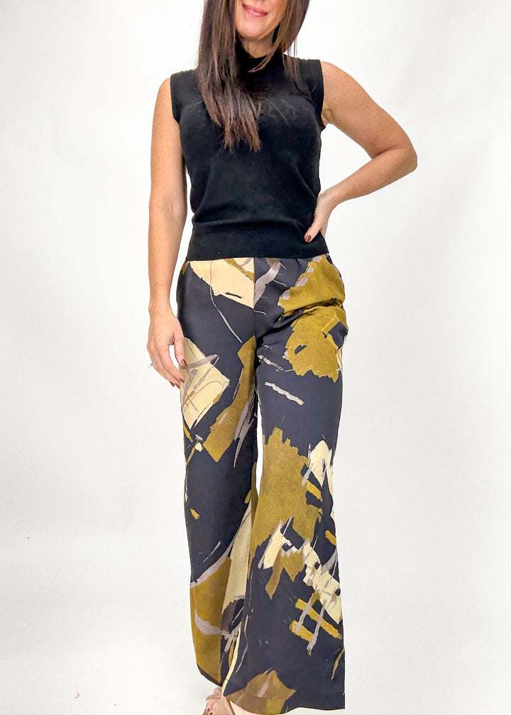 Woman wearing a black sleeveless top and patterned pants on a white background