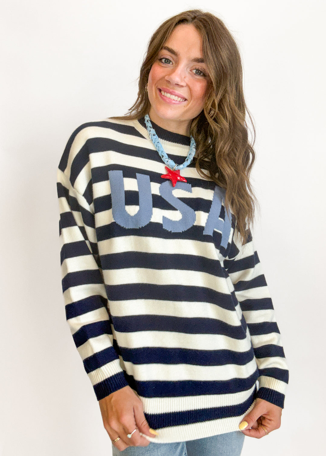 Woman wearing a striped sweater with 'USA' text on a plain background